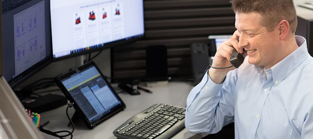 Photo person at desk on phone in front of computer